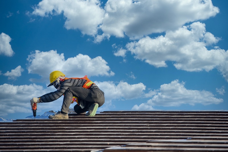 Worker repairing roof under blue sky in Toledo, Ohio