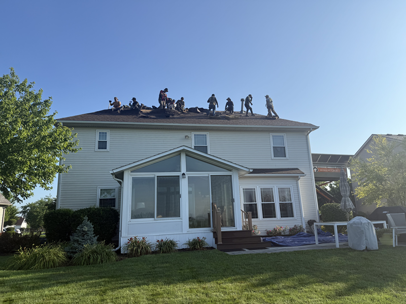 Roofing crew working on a residential roof during summer roof replacement