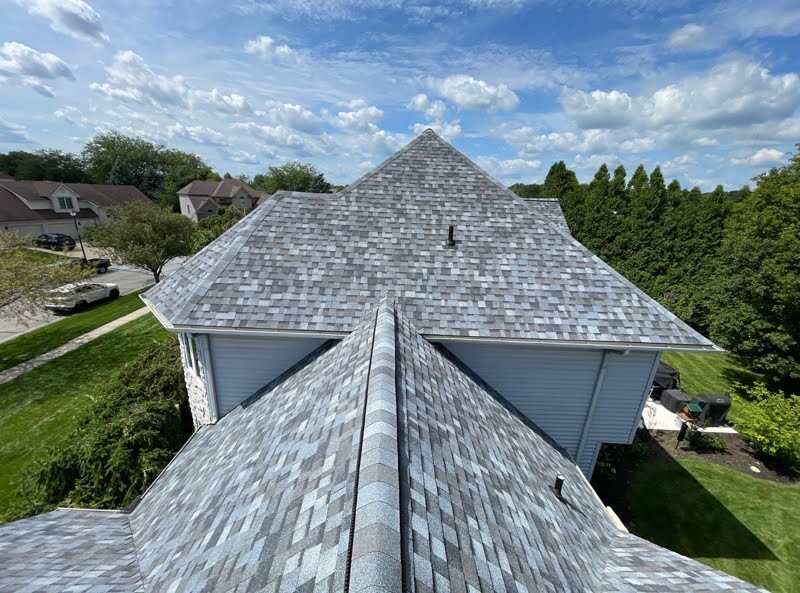 Light gray architectural asphalt shingle roof with intersecting hips and ridge caps